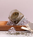 Esfoliante corporal de sal marinho, cristais de menta e hortelã-pimenta, da SLOW, feito à mão em Portugal com gelo num prato de madeira com a tampa aberta